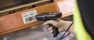 Mit einem Handscanner wird ein Etikett an einem Regal gescannt.