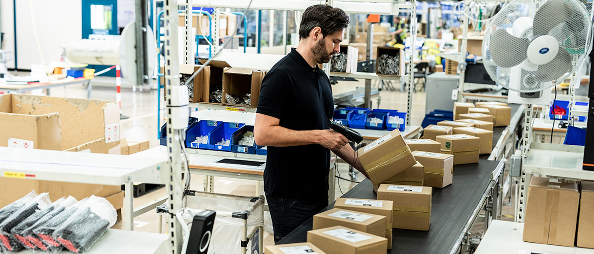MANN EINE EINEM FÖRDERBAND SCANNT Barcodes auf Paketen.