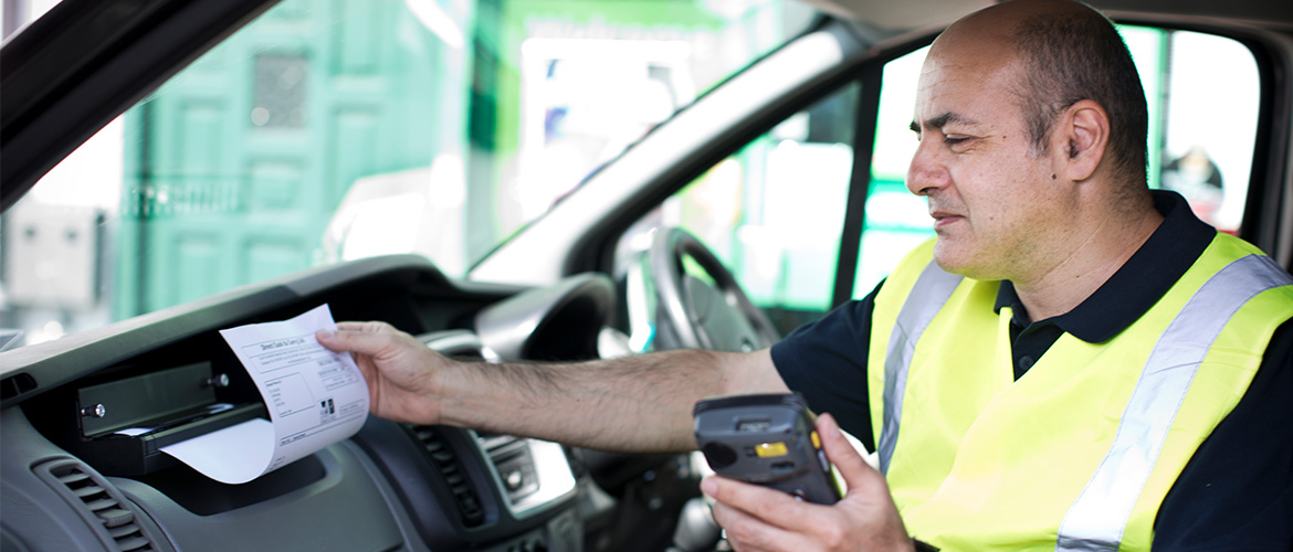 LKW-Fahrer in Fahrerkabine druckt ein Dokument von seinem Handy auf einem mobilen Drucker aus.