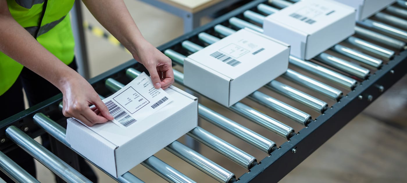 Mann eteketiert Packete am Fließband