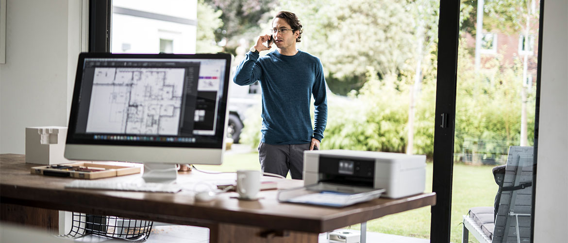 MANN TELEFONIERT IM HOME OFFICE, BILDSCHJ UND DRUCKER IMADERGRUND