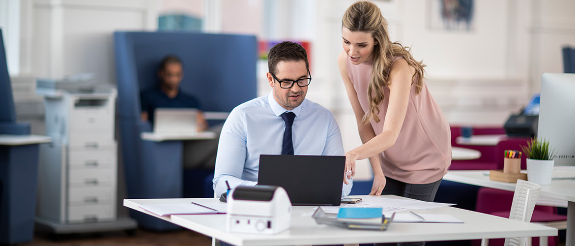 Frau Erklärt Mann etwas ein Laptop Bildschirm im Büro.