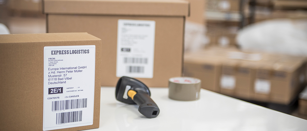 Versandkartons im Lager mit Versandetiketten und Barcode-Scanner