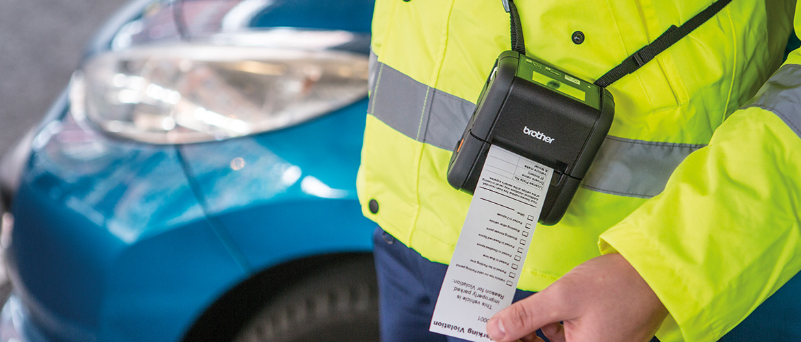 Mitarbeiter einseitig ordnungssamtes Druckt mit Brother etikettendrucker einen strefzettel, Auto im Hintergrund.
