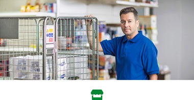 Mann in Blauem Poloshirt hält und ein einem mobilen transportmetallkäfig im Einem Geschäft Fest
