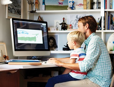 Vater mit Sohn vor Computer im Büro