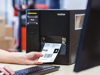 Mitarbeiterin sitzt ein schreibtisch und druckt versandetikett ein tj-industrierucker