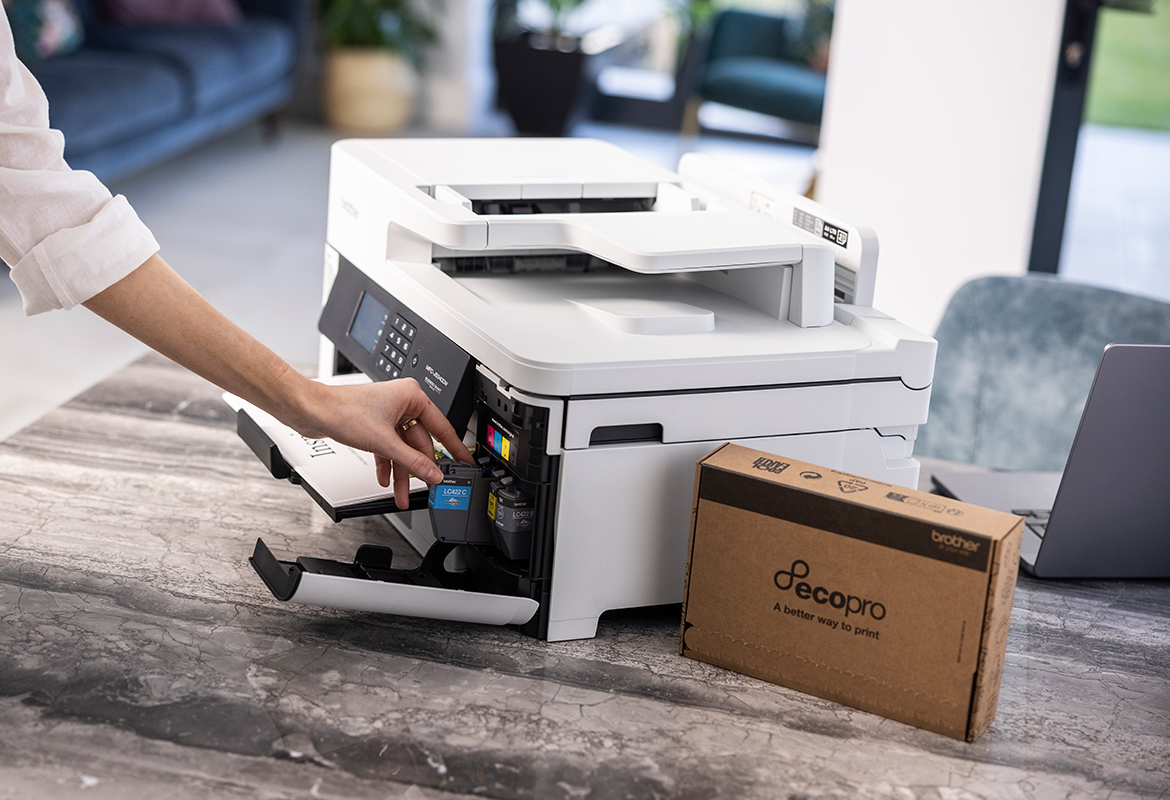 Frau, die eine Tintenpatrone in einen Drucker auf einem Tisch mit einer EcoPro-Box daneben einlegt