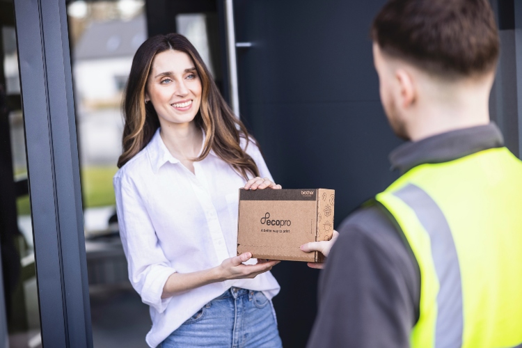  Ein Lieferant mit gelber Warnweste übergibt einer Frau ihr bestelltes EcoPro Paket. 