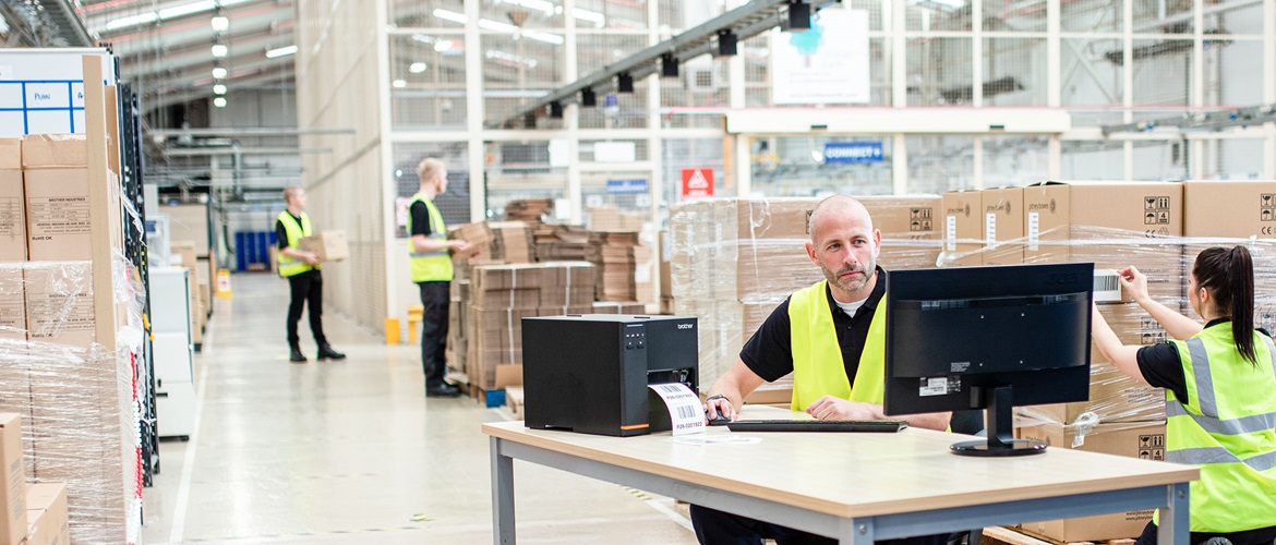 Mann in hoher Sichtbarkeitsweste saß am Schreibtischdruck auf dem Drucker von TJ Industrial Label-Drucker im Lager